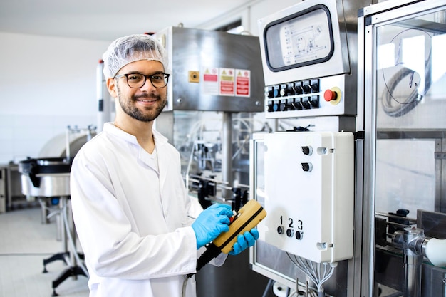 Portrait of technologist standing by industrial machine in pharmaceutical company or factory