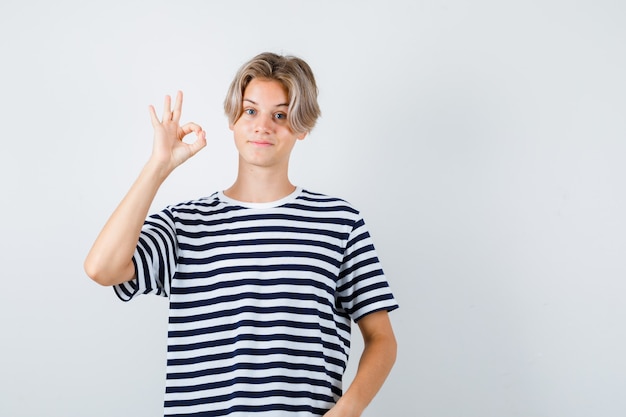 Portrait of teen boy showing ok gesture in t-shirt and looking pleased front view