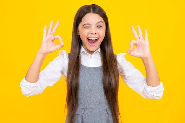 Portrait of teen girl making ok gesture isolated background Young teenager smiling and giving okey