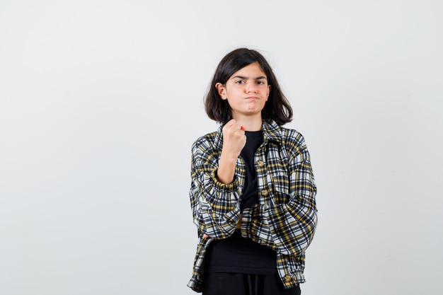 Portrait of teen girl warning with clenched fist in casual shirt and looking aggressive front view