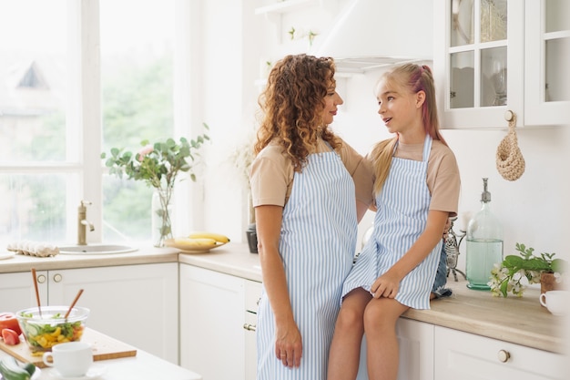 Portrait of a teen girl with her mother at home in kitchen