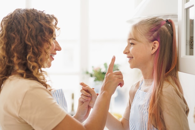 Portrait of a teen girl with her mother at home in kitchen