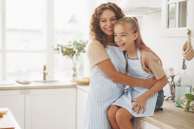 Portrait of a teen girl with her mother at home in kitchen