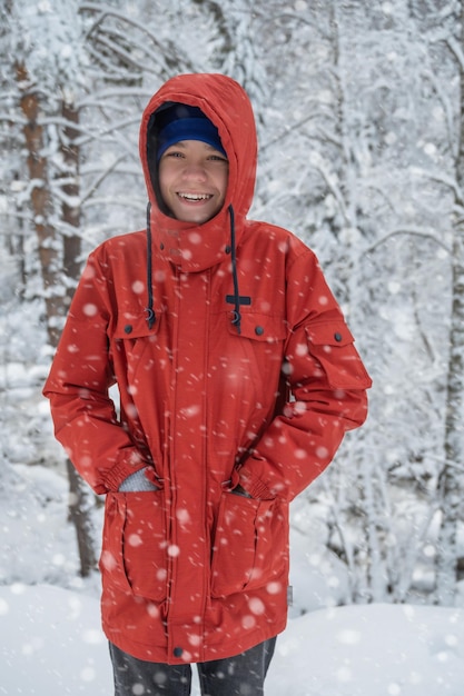 Portrait of teenage boy walking and having fun in winter snowing forest