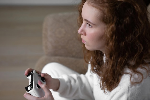 Portrait of a teenage girl Generation Z playing a video game at home on a console