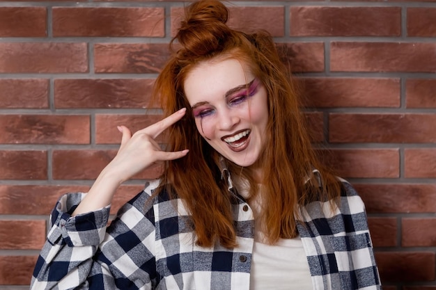 Portrait of a teenage girl generation Z with red hair and bright makeup smiling