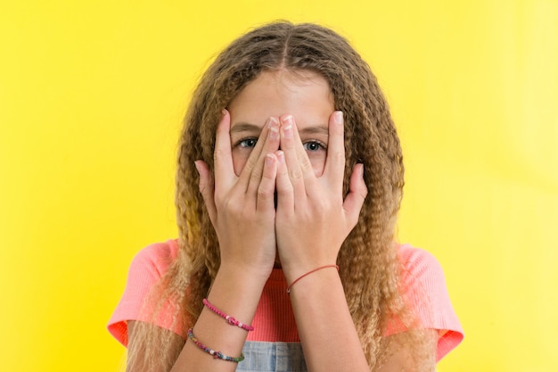 Portrait of teenage girl peeps through fingers