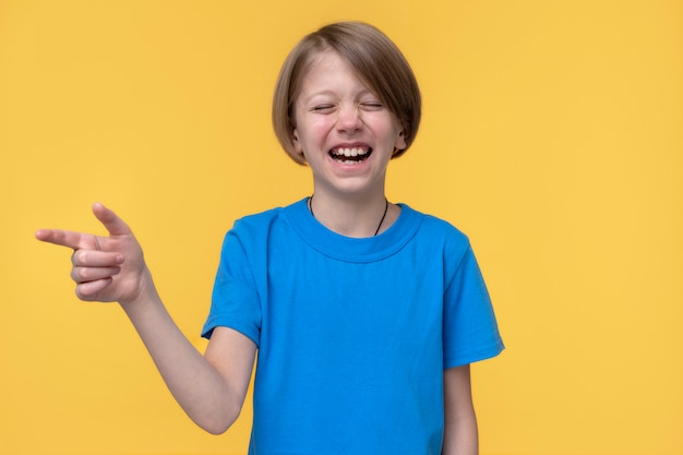 Portrait of teenage girl smiling with mouth wide open and pointing to the left