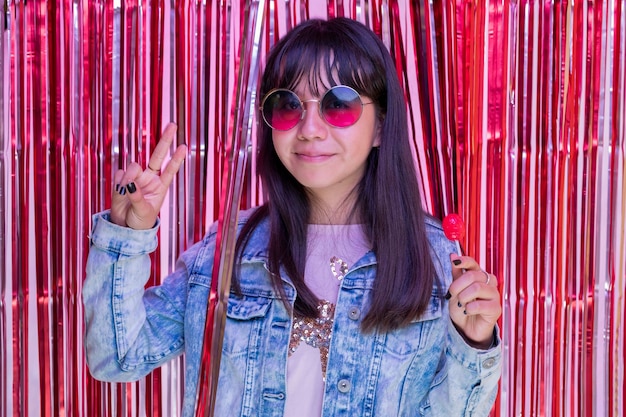 Portrait of teenage girl wearing sunglasses and making peace and love sign with fingers