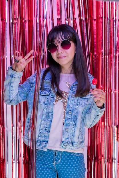 Portrait of teenage girl wearing sunglasses and making peace and love sign with fingers