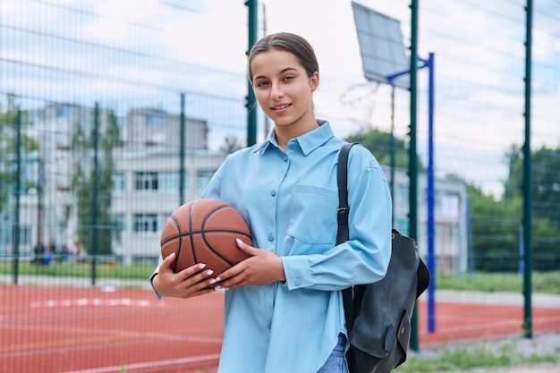 Portrait of teenage student girl with backpack and basketball ball