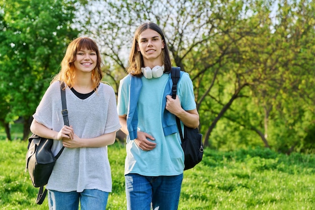 Portrait of teenage young guy and girl students looking at camera outdoor copy space