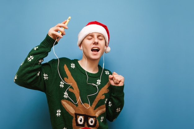 Portrait teenager boy with Christmas sweater listening music