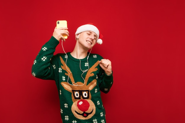 Portrait teenager boy with Christmas sweater listening music