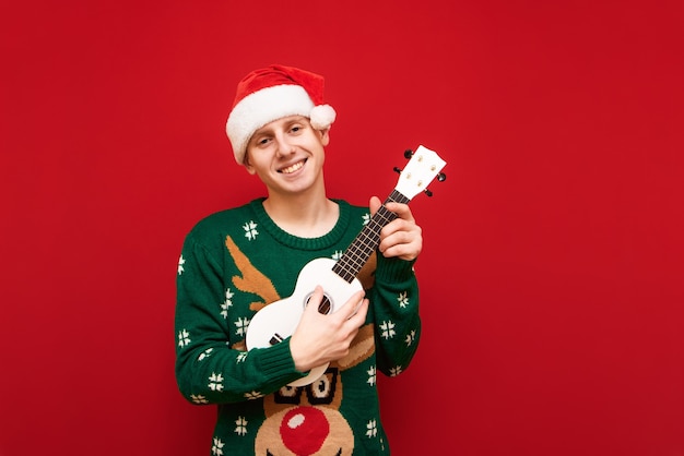 Portrait teenager boy with Christmas sweater with ukulele