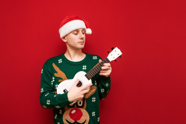 Portrait teenager boy with Christmas sweater with ukulele