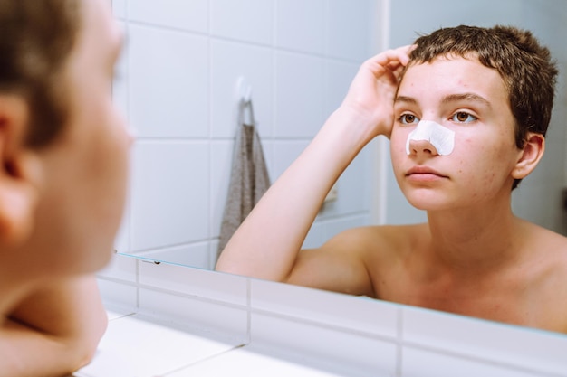 Portrait of teenager girl, with short hairstyle, looking in mirror, cleansing face with nasal strips