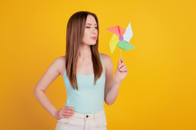 Portrait of tender tempting lady hold toy propeller blow air kiss on yellow background