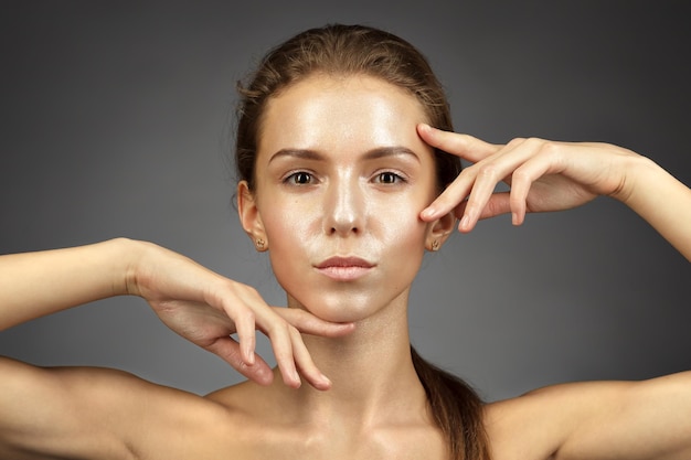 Portrait of a thin and beautiful caucasian girl with a shiny perfect skin She holds a finger near her chin