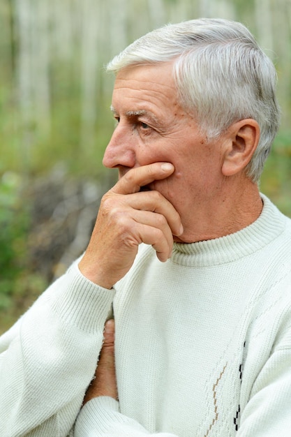 Portrait of thinking senior man on autumn background