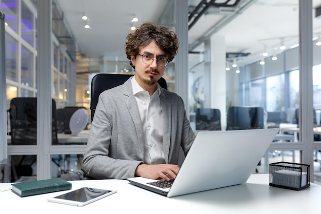 Portrait of thinking serious businessman inside office bearded man looking into camera focused in