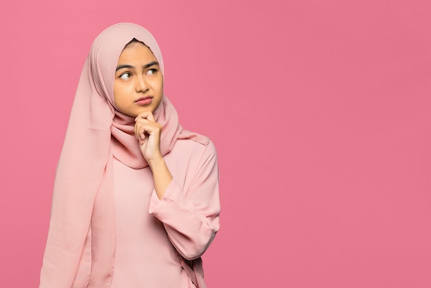 Portrait of thinking young Asian woman looking up and touch chin