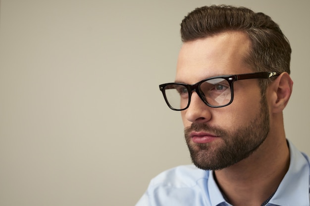 Portrait of a thoughtful handsome Caucasian man wearing spectacles looking into the distance