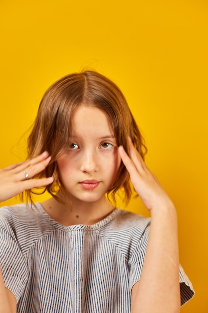 Portrait of a Thoughtful Teenage Schoolgirl Against a Vibrant Yellow Background