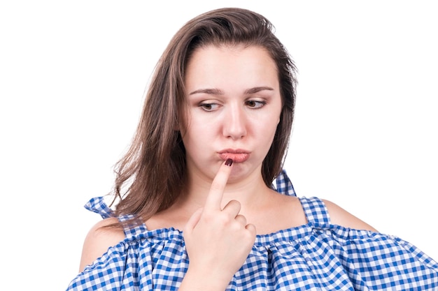 Portrait of a thoughtful woman with pouting lips and finger at mouth isolated on white background