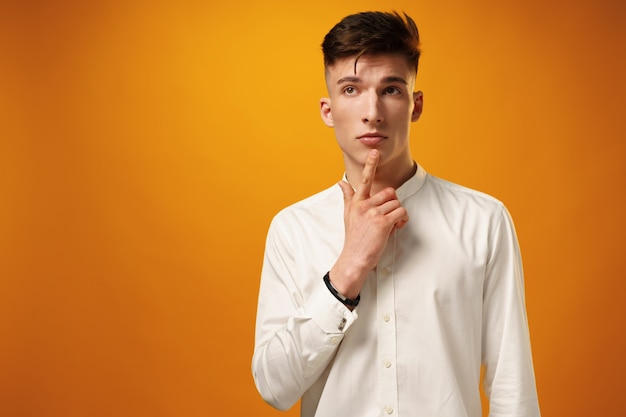 Portrait of thoughtful young man who looks away touching his chin