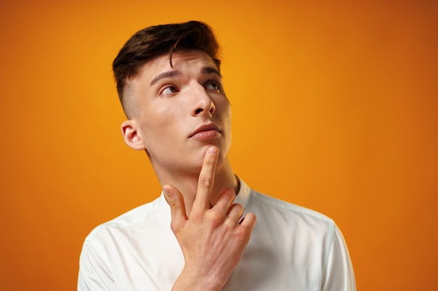 Portrait of thoughtful young man who looks away touching his chin