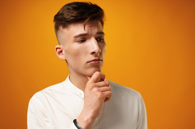 Portrait of thoughtful young man who looks away touching his chin