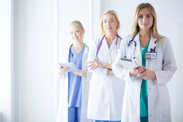 Portrait of three confident female doctors standing with arms crossed at the medical office