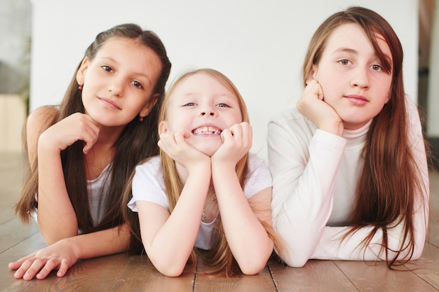 Portrait of three female friends laying and laughing on the floor