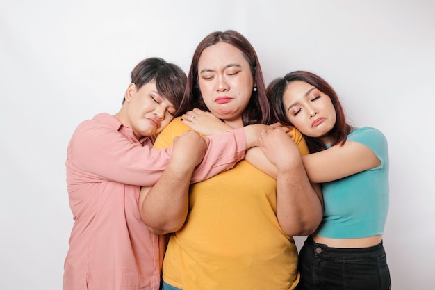 A portrait of three friends looking sad crying wiped her tears and hug each other isolated white background