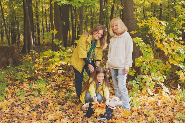 Portrait of three generations of happy beautiful woman and dog in autumn nature.