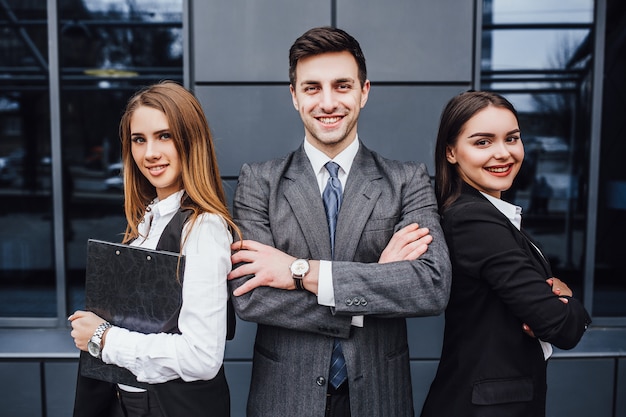 Portrait of three young smiling lawyers standing crossed arms.