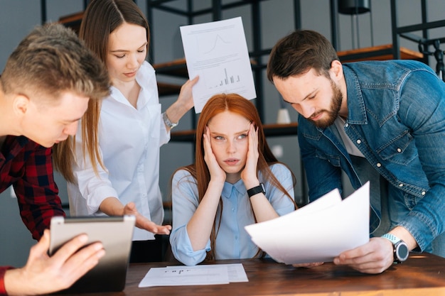 Portrait of tired business woman sitting at table multiethnic colleagues shaking documents