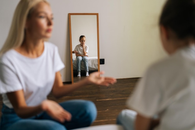 Portrait of tired young woman sadness looking at camera sitting on bed on background of aggressive husband shouting on girlfriend at home