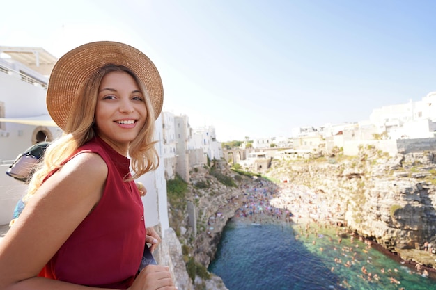 Portrait of tourist girl looking at camera from terrace in Polignano a mare Apulia Italy Wide angle