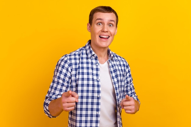 Portrait of trendy brunet positive guy in shirt having open mouth pointing forefingers front isolated bright background