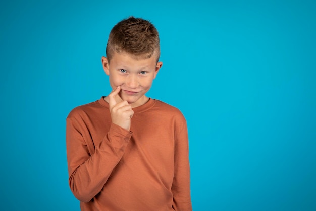 Portrait of tricky preteen boy touching chin and looking at camera