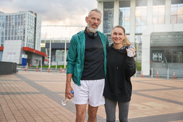 Portrait of two active middle aged sportive people in sportswear walking together outdoors after