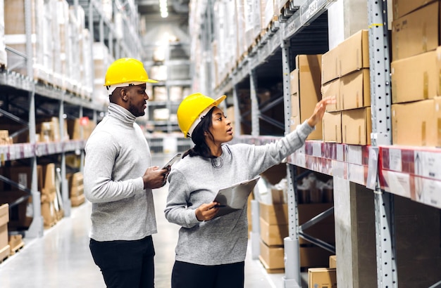 Portrait two african american engineer team shipping order detail on tablet check goods and supplies on shelves with goods inventory in factory warehouse.logistic industry and business export