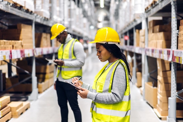 Portrait two african american engineer team shipping order detail on tablet check goods and supplies on shelves with goods inventory in factory warehouselogistic industry and business export