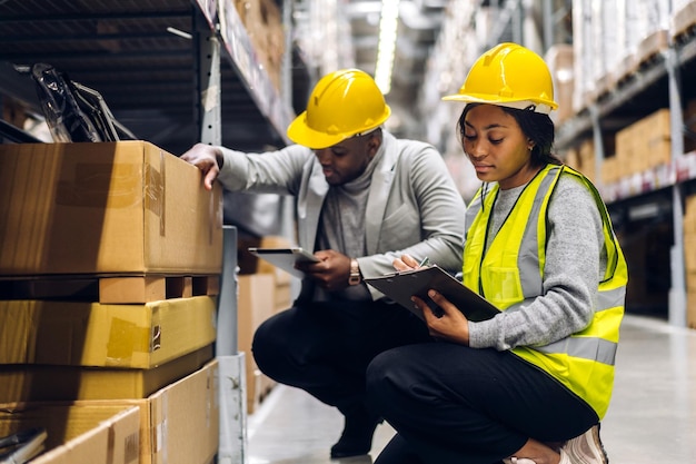 Portrait two african american engineer team shipping order detail on tablet check goods and supplies on shelves with goods inventory in factory warehouselogistic industry and business export