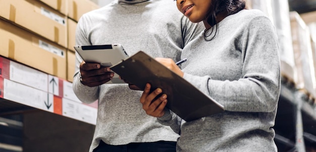 Portrait two african american engineer team shipping order detail on tablet check goods and supplies on shelves with goods inventory in factory warehouselogistic industry and business export