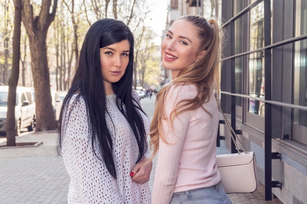 portrait of two beautiful girlfriends who turned to the camera on a city street