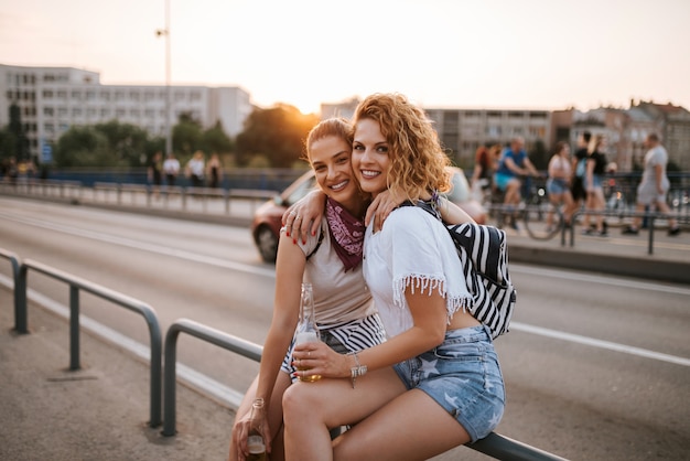 Portrait of a two beautiful young female friends hugging on the summer music festival.