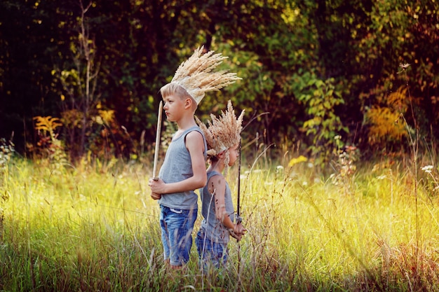 Portrait Two Brothers have a crown from dry grass on the head and swords in hands. Joy and play concept